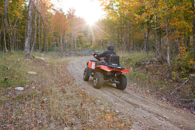 A man rides his ATV on through the forest at Jericho Mountain State Park in Berlin, New Hampshire.  White Mountains.
