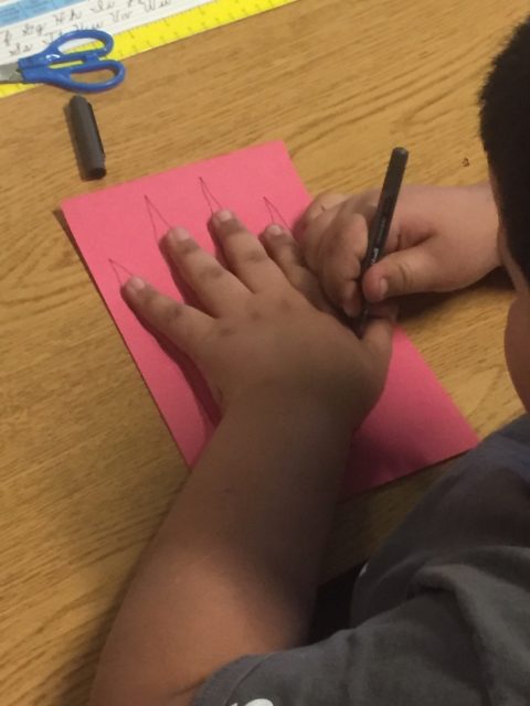 A student traces his hand to create a 'leaf.'