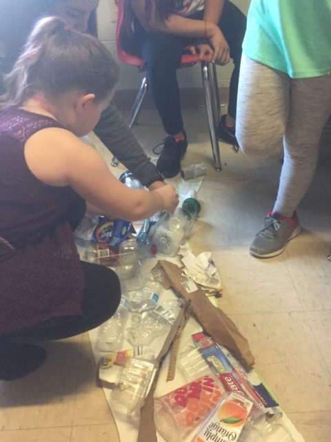 Students place plastic on the trunk of the Recycle Tree.