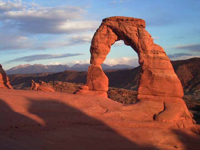 A red rock arch rises into the sky.